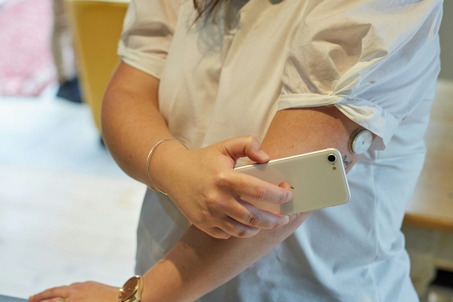Woman using a CGM to monitor blood sugar, syncing it with her phone.